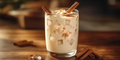 Creamy cinnamon iced drink served in a glass with ice and garnished with cinnamon sticks on a wooden table photo