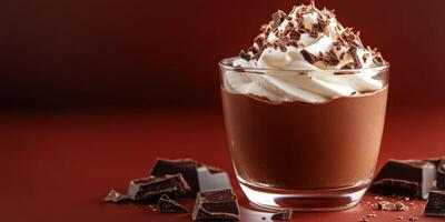 Decadent chocolate mousse dessert topped with whipped cream and shavings served in a glass on a wooden surface photo