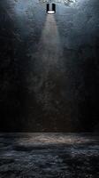 Dramatic lighting illuminates an empty stage with a textured black background in a minimalistic setting photo