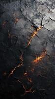 Cracks in volcanic rock reveal glowing magma in a dark, textured landscape photo