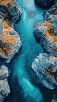 Vibrant blue river flows between rocky cliffs in a serene landscape view from above at sunset photo