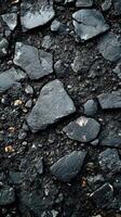 Dark textured asphalt surface with broken stone fragments scattered across the ground photo