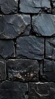 Textured black stone wall showcasing diverse shapes and sizes of stones in a natural arrangement photo