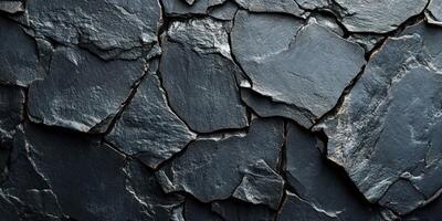 Textured black slate rocks arranged closely on a surface in a natural layout created by geological processes photo