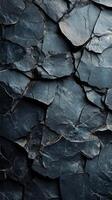 Dark slate rock surface displaying unique textures and geological patterns with shades of gray and blue in natural light photo