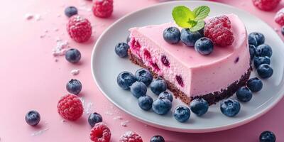 Delightful raspberry and blueberry cheesecake served on a white plate with fresh fruits and mint leaf garnish photo