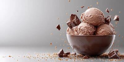 Chocolate ice cream scoops in a brown bowl with chocolate chunks scattered around photo