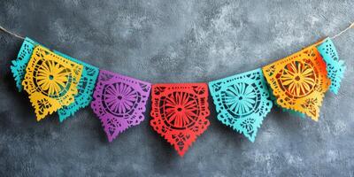 Colorful papel picado decorations hang against a textured gray background to celebrate a festive occasion with vibrant designs and patterns photo