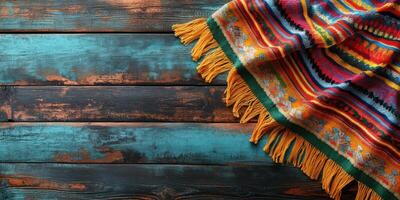 Colorful woven blanket draped over rustic wooden surface featuring bright hues and intricate patterns photo
