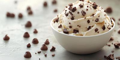 Delicious vanilla ice cream topped with chocolate chips in a white bowl on a textured surface photo