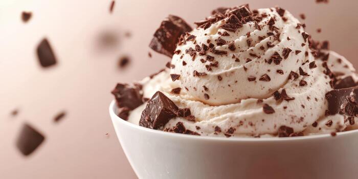 Delicious chocolate ice cream topped with whipped cream and chocolate chunks served in a bowl photo