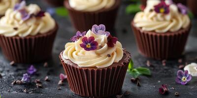 Delightful chocolate cupcakes decorated with cream frosting and edible flowers on a dark surface photo