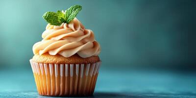 Delicious cupcake topped with creamy frosting and mint leaf on a blue background in a cozy setting photo