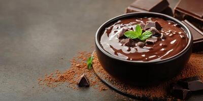 Creamy chocolate mousse topped with chocolate chunks and fresh mint on a dark surface photo