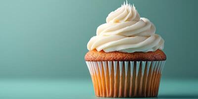 Delicious vanilla cupcake with creamy frosting on a turquoise background showcasing its texture and color photo