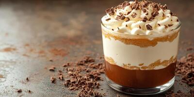 Delicious layered dessert with chocolate, cream, and crushed toppings in a clear glass on a textured surface photo