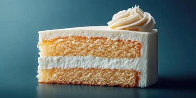 Slice of fluffy vanilla cake with creamy frosting on the top displayed on a dark background photo