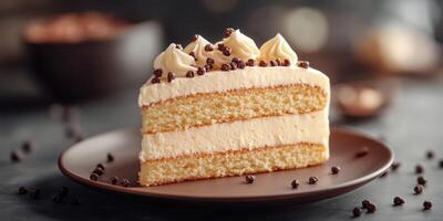 Layered vanilla cake with creamy frosting and chocolate sprinkles served on a dark plate photo