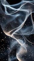 Ethereal wisps of smoke dance gracefully in a dark setting, illuminated by soft light and sparkling particles photo