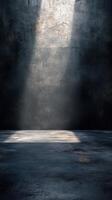Moody light beams illuminate an empty dark room with textured walls and a concrete floor photo