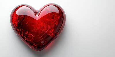 Shiny red heart object resting on a smooth white surface, symbolizing love and affection in a minimalist setting photo