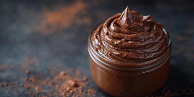 Chocolate spread in a glass jar with rich, creamy texture and cocoa powder on a dark surface photo