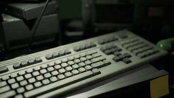 Old computer keyboard placed on a cluttered desk with other equipment video