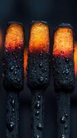 Close-up of glowing matchsticks with droplets, showcasing intense colors and textures in a dark setting photo