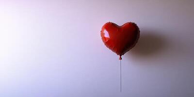 Heart-shaped red balloon floating against a plain background is a symbol of love and celebration photo