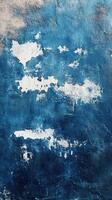 Textured blue wall with fading white patches resembling clouds in a weathered urban setting photo