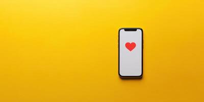 Modern mobile device displays heart icon on a vibrant yellow background, symbolizing love and connection photo