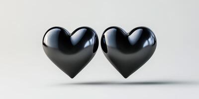 Two glossy black heart shapes sitting side by side on a light background symbolizing love and connection photo