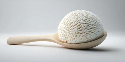 Creamy white ice cream sits on a wooden spoon against a simple background photo
