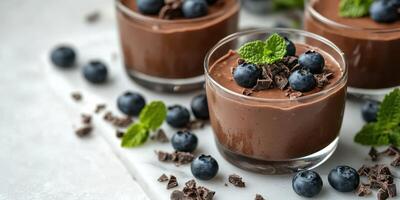 Chocolate mousse dessert with fresh blueberries and mint leaves arranged on a marble surface photo