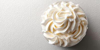Whipped cream swirl in a clear cup on a textured white surface captured in a cozy kitchen setting photo