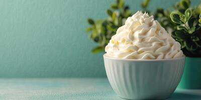 Delicious whipped cream topping served in a bowl against a calming teal background with greenery photo