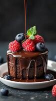 Decadent chocolate cake with fresh berries and mint on a dark background photo