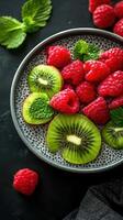 Fresh fruit bowl with kiwi and raspberries garnished with mint leaves captured in a textured bowl photo