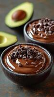 Creamy chocolate avocado mousse topped with chocolate chips served in rustic bowls photo