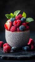 Fresh berries in a textured bowl with mint leaves on a dark background create a vibrant and healthy dessert option photo