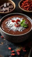 Delicious chocolate pudding topped with coconut, goji berries, and mint leaves in a rustic bowl photo
