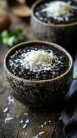 Delicious black bean soup topped with shredded coconut and served in rustic bowls on a wooden table photo