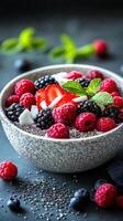 Colorful berry bowl garnished with mint and coconut on dark background photo