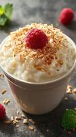 Delicious creamy dessert topped with toasted coconut and fresh raspberries on a dark background photo