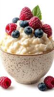 Creamy dessert topped with fresh berries and a mint leaf in a speckled bowl photo