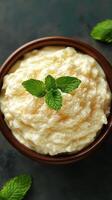 Creamy dessert topped with mint leaves served in a rustic bowl on a dark background photo
