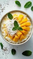 Creamy coconut rice pudding topped with fresh mango and mint leaves served in a bowl photo