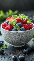 Fresh mix of berries in a decorative bowl garnished with mint leaves captured in a bright kitchen setting photo