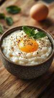 Creamy rice dish topped with a fresh egg yolk and mint leaves in a rustic bowl on a wooden surface photo
