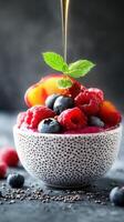 Fresh fruit bowl with raspberries, blueberries, and mint surrounded by a drizzle of honey on a dark surface photo